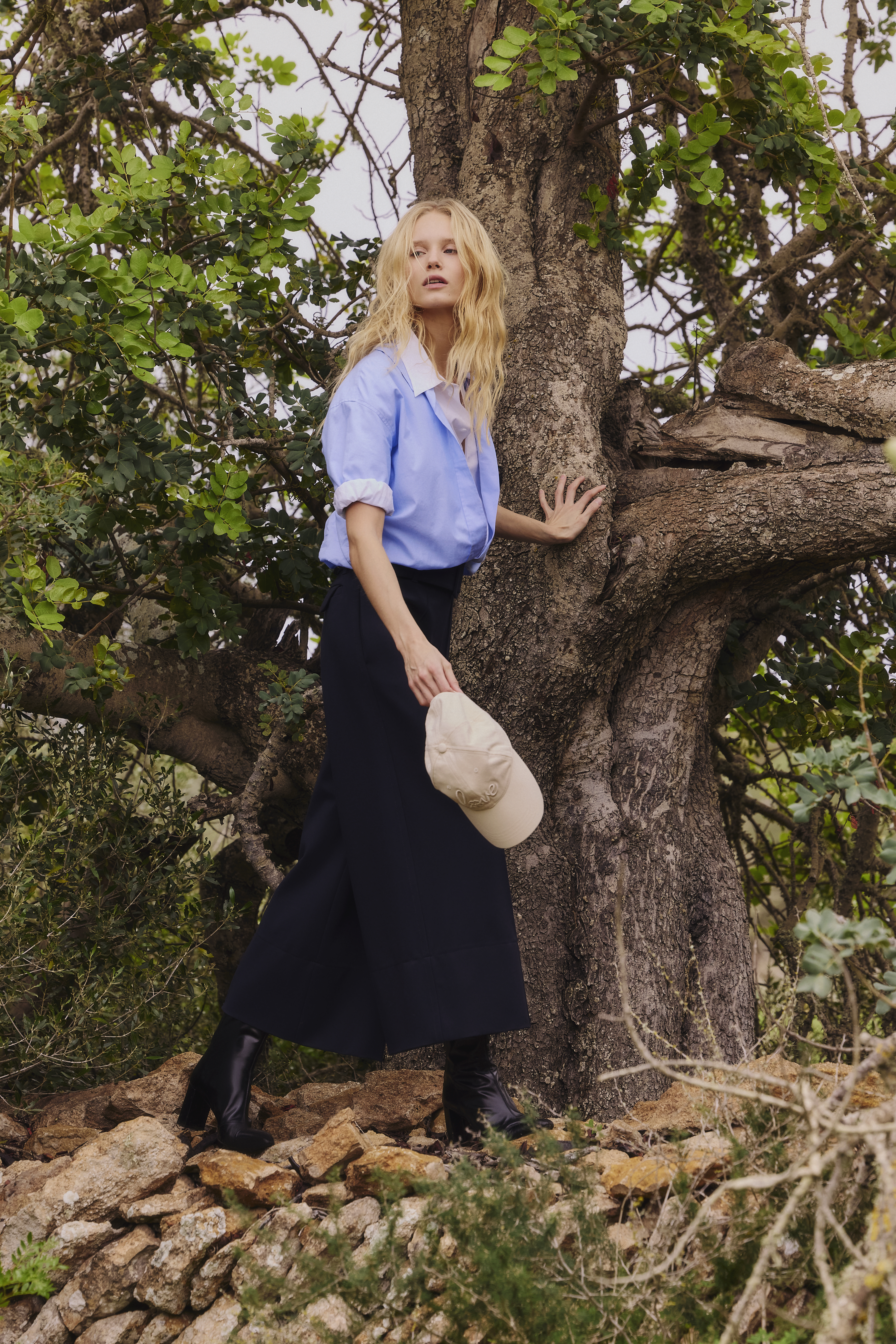 Woman standing next to a tree wearing a layered Blouse and a dark navy culotte both from dorothee schumacher