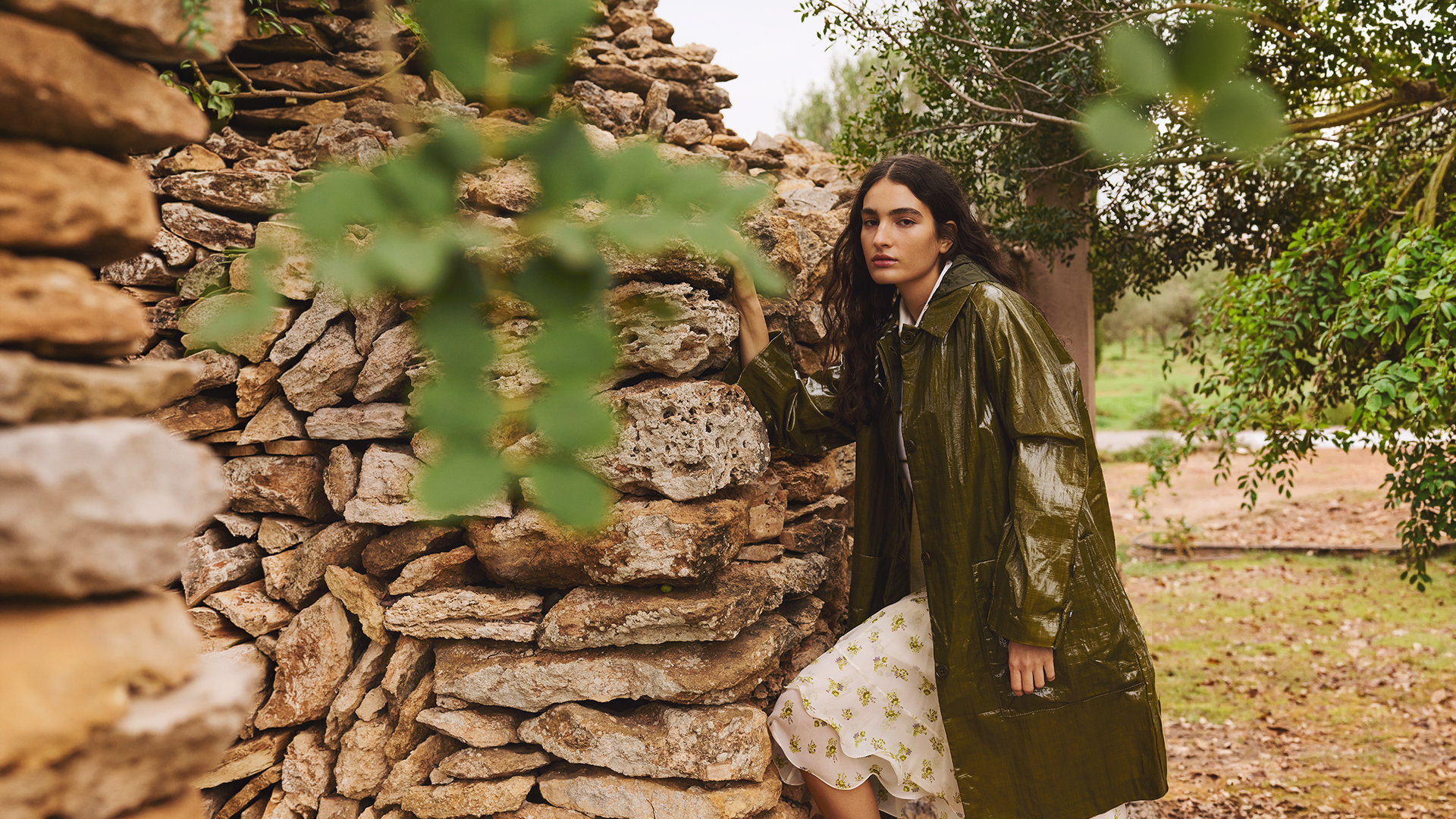 Woman standing next to a stone wall in a Dorothee Schumacher Raincoat 