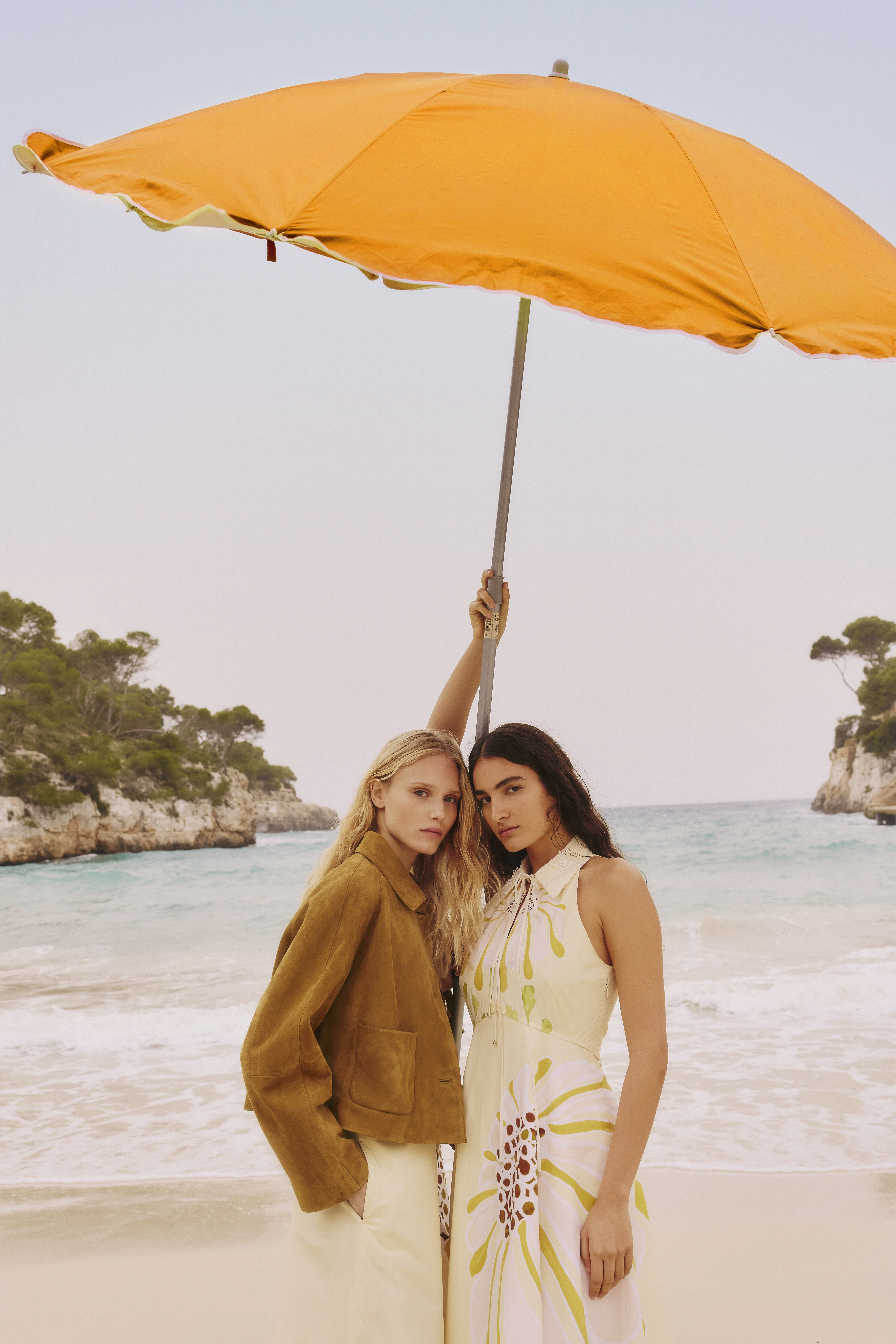Two Woman at the beach wearing dorothee schumacher looks and holding an umberella 
