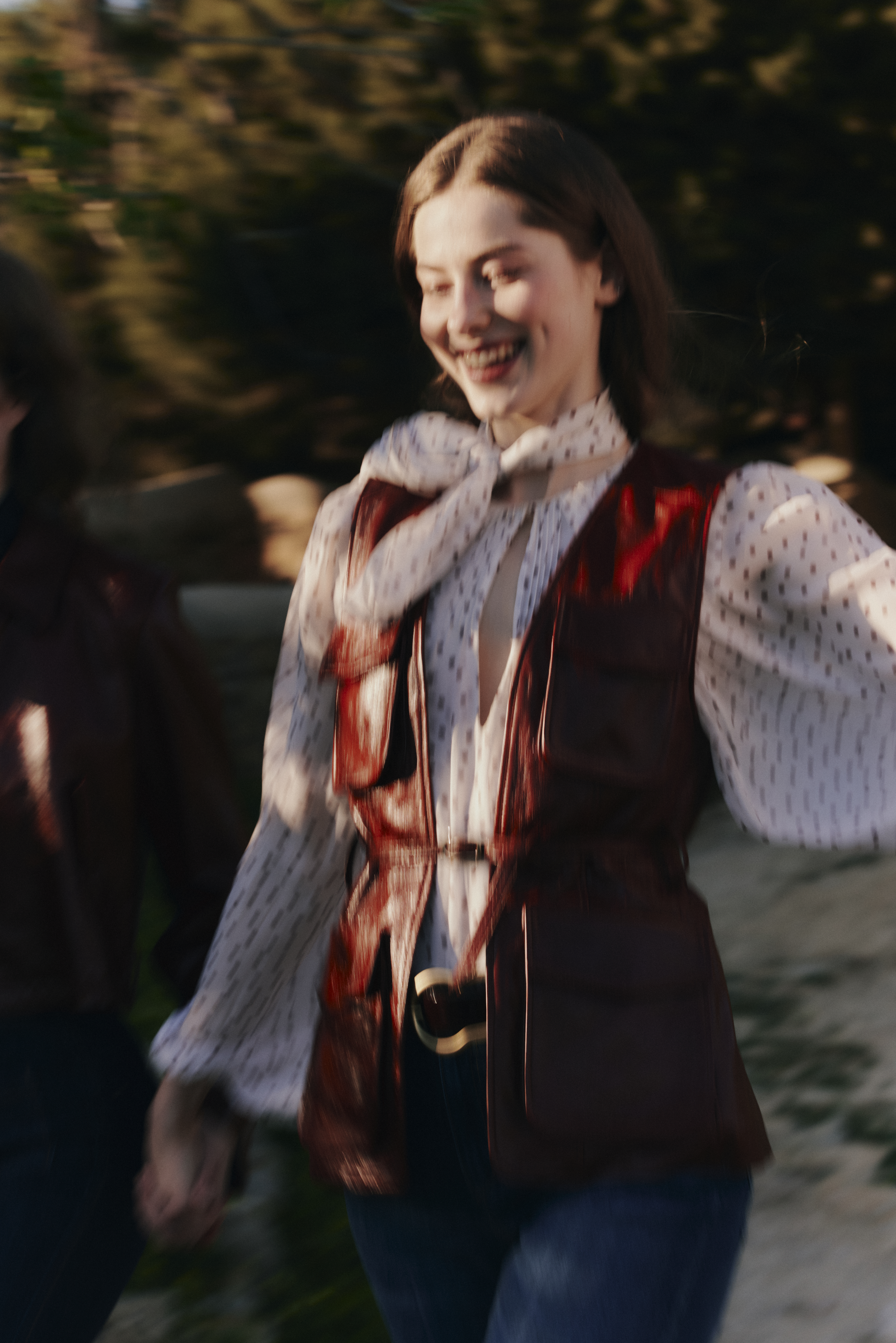 A Model wearing a bordeaux leather vest and polka dot blouse from DOROTHEE SCHUMACHER running