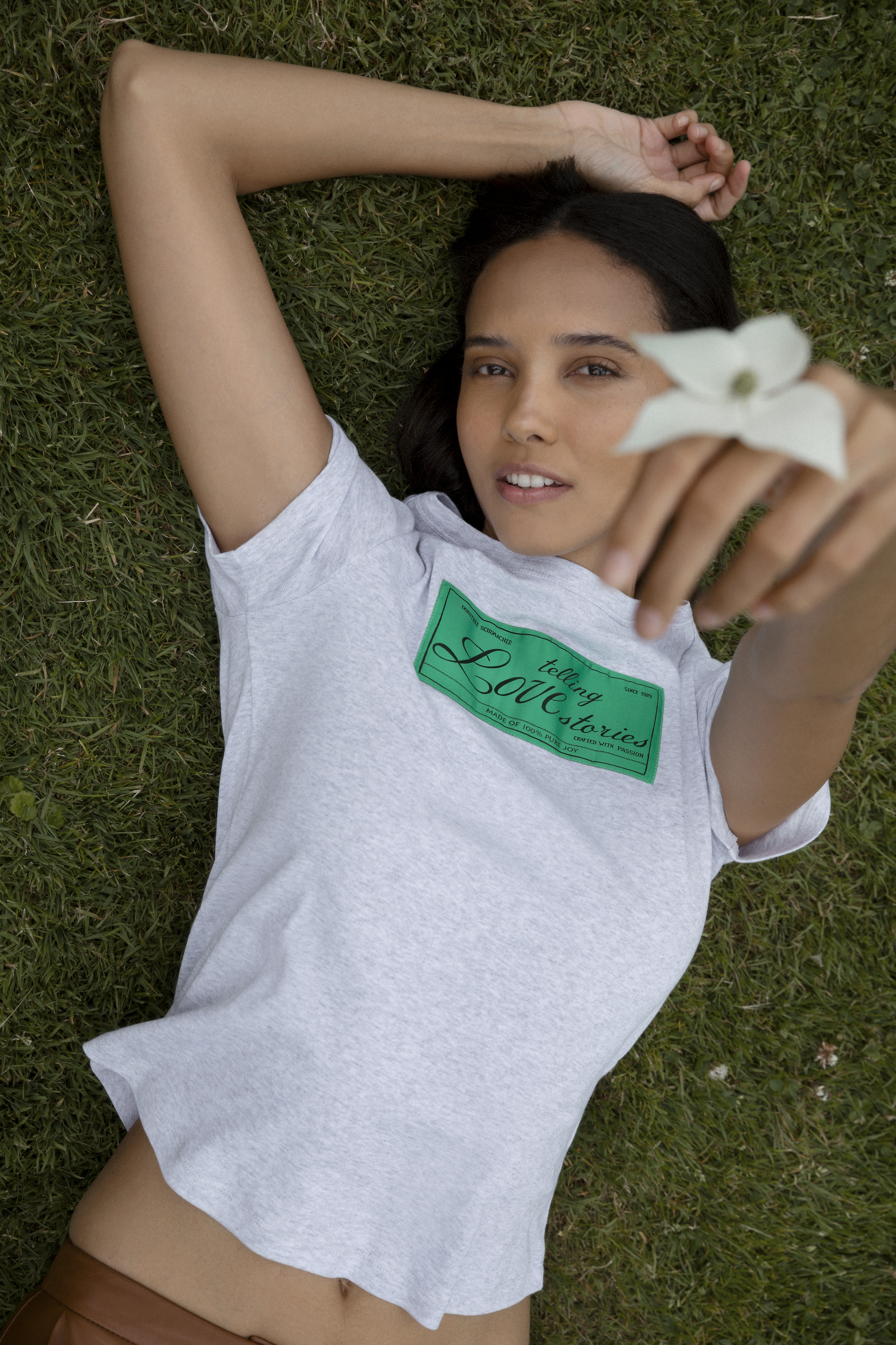 Model wearing a grey t-shirt with a green label saying "telling Lovestories" from the german fashion brand DOROTHEE SCHUMACHER