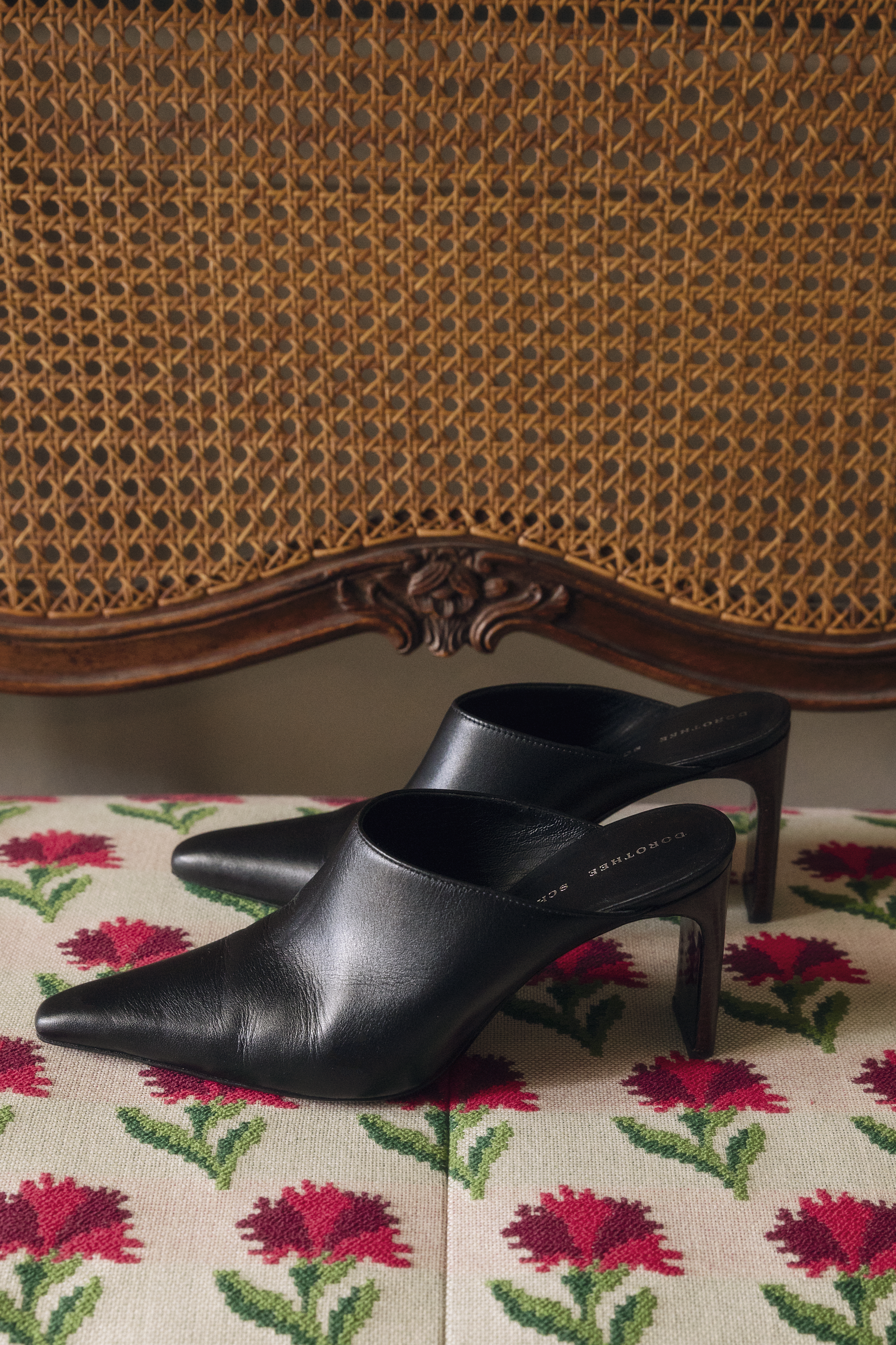 Black Mule Shoe from the fashion brand DOROTHEE SCHUMACHER placed on a vintage rattan chair