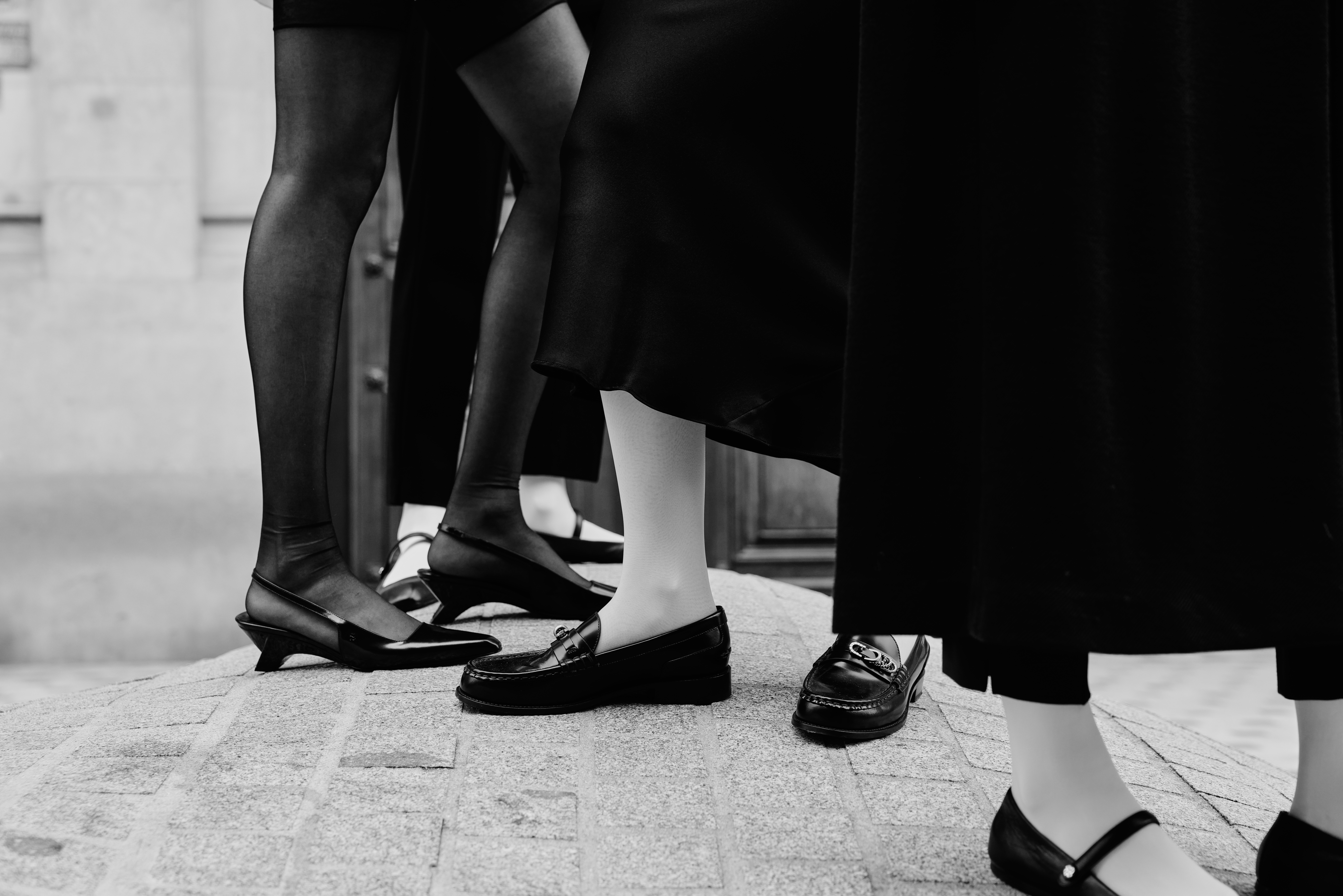 3 pair of legs shown wearing neutral clothes and black expensive leather shoes