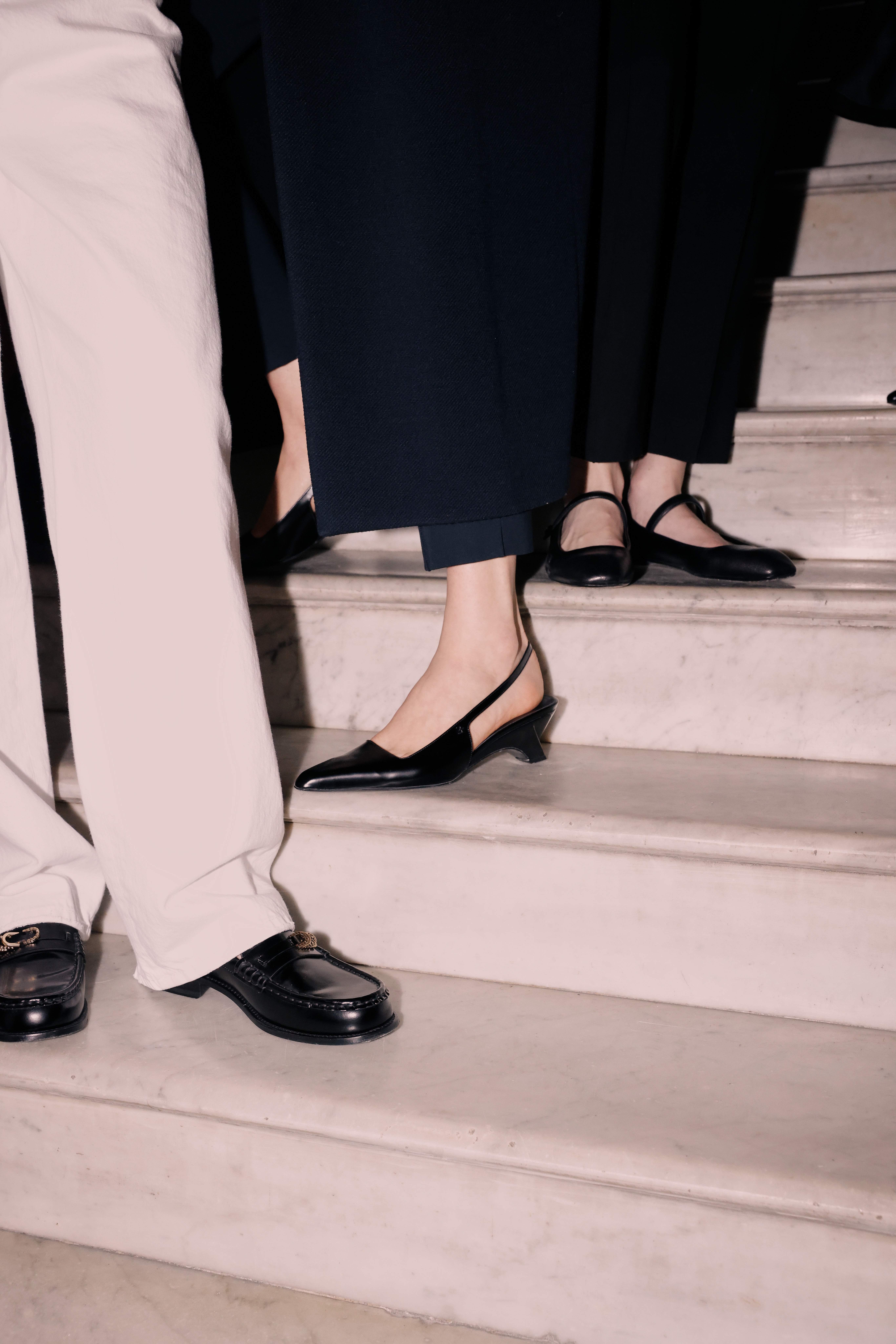 Pair of feet standing on stairs wearing black leather shoes