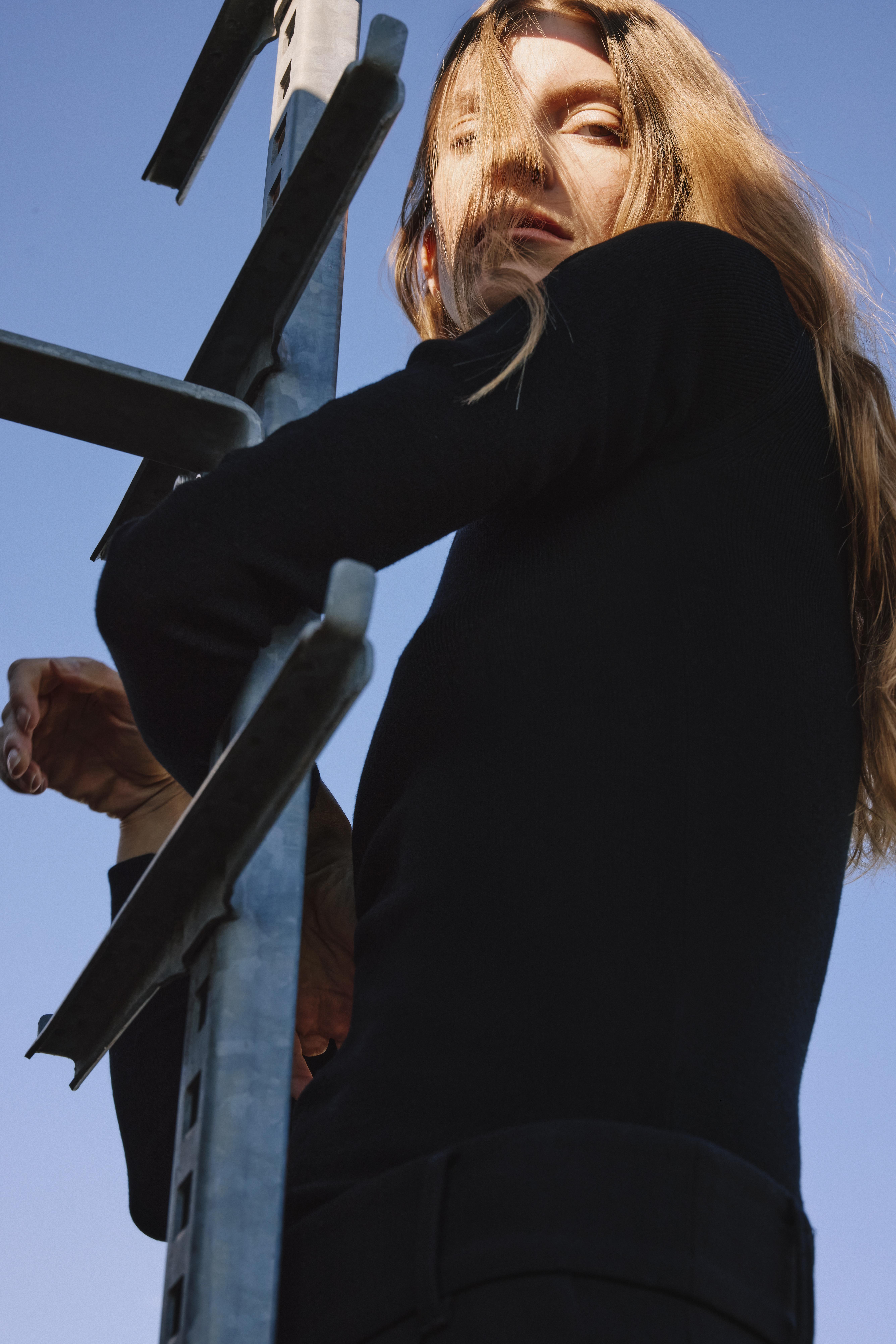 Woman in a black dress and red hair looking in the sun