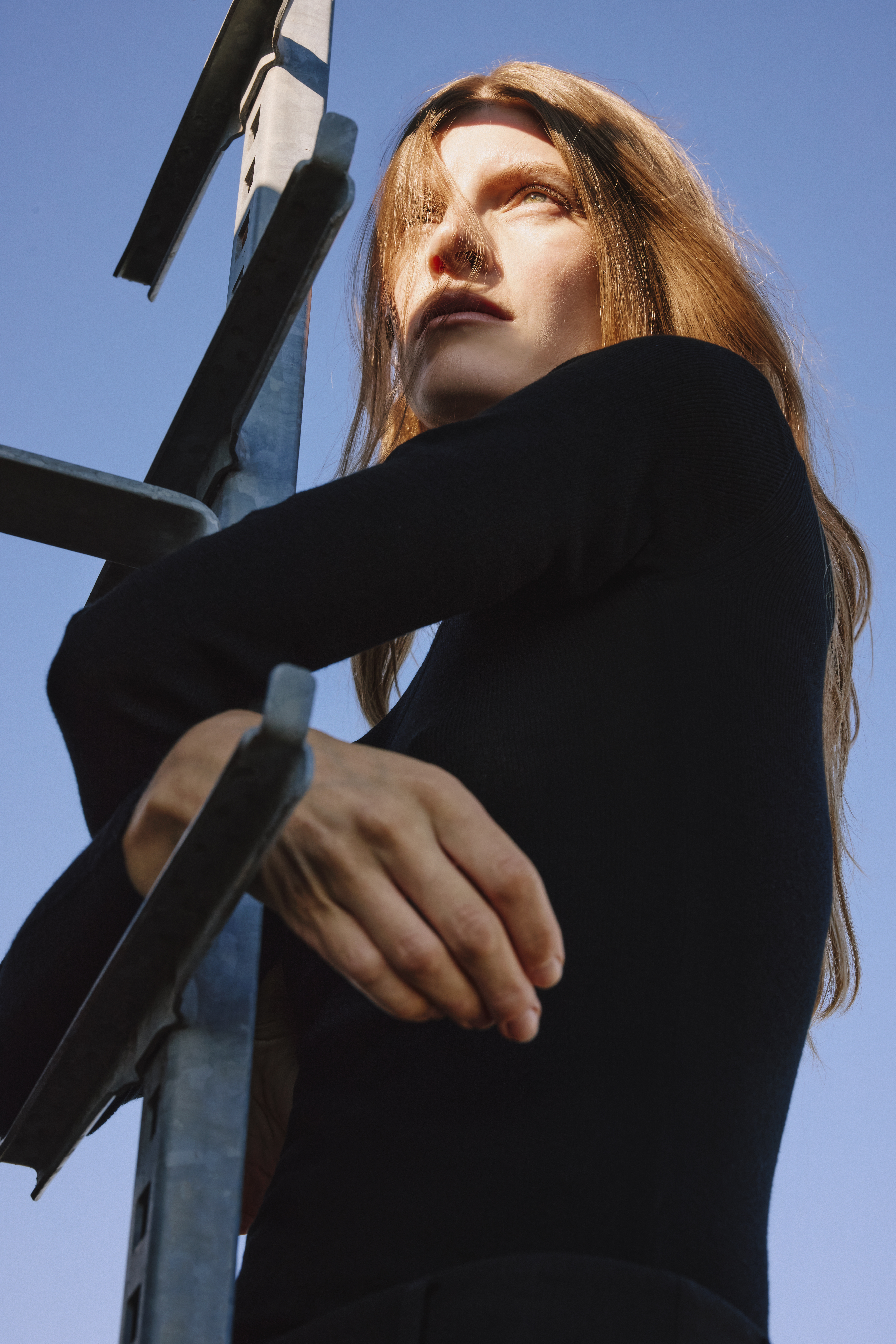 Woman in a black dress and red hair looking in the sun