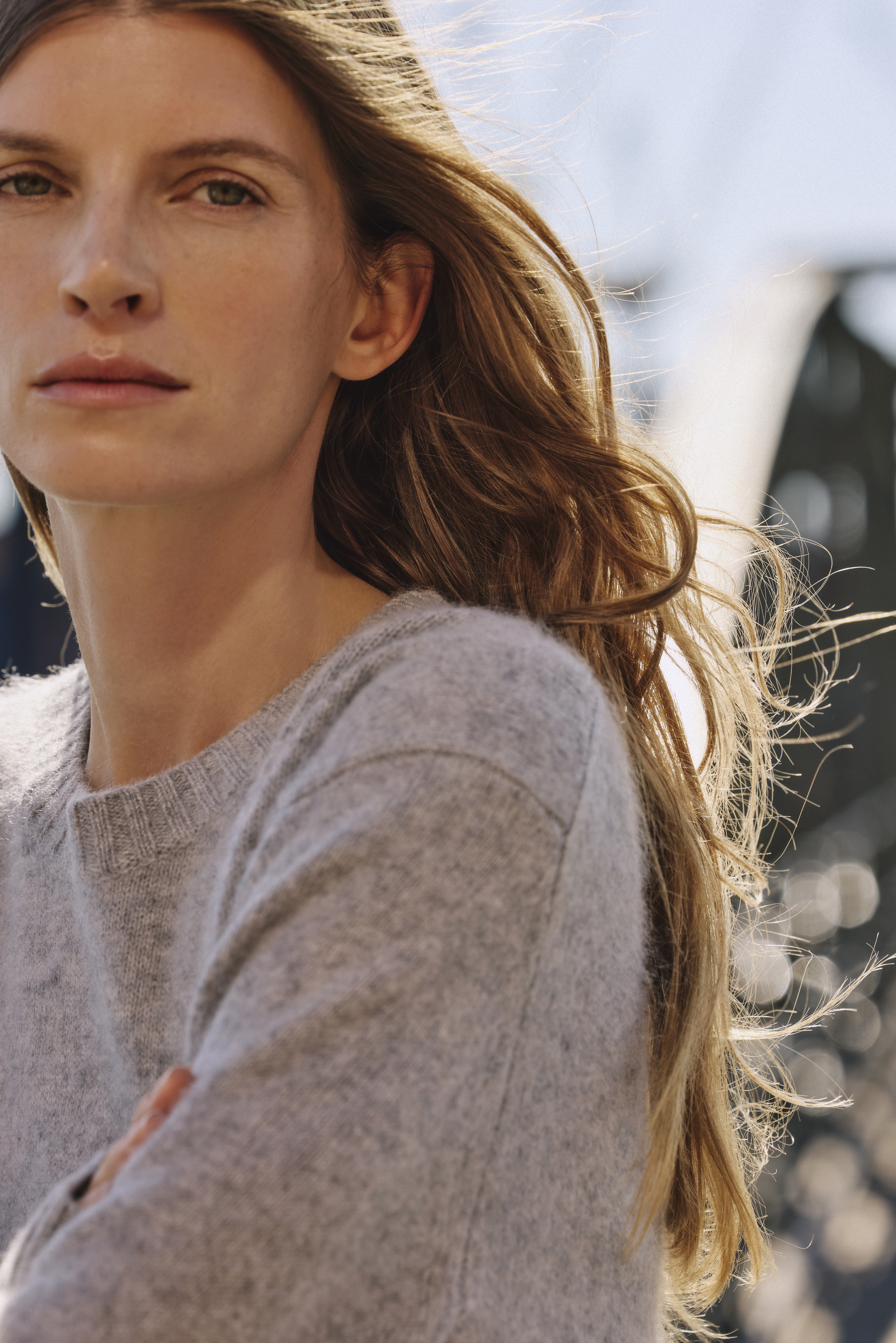 a woman looking in the camera and wearing a grey cozy looking pullover