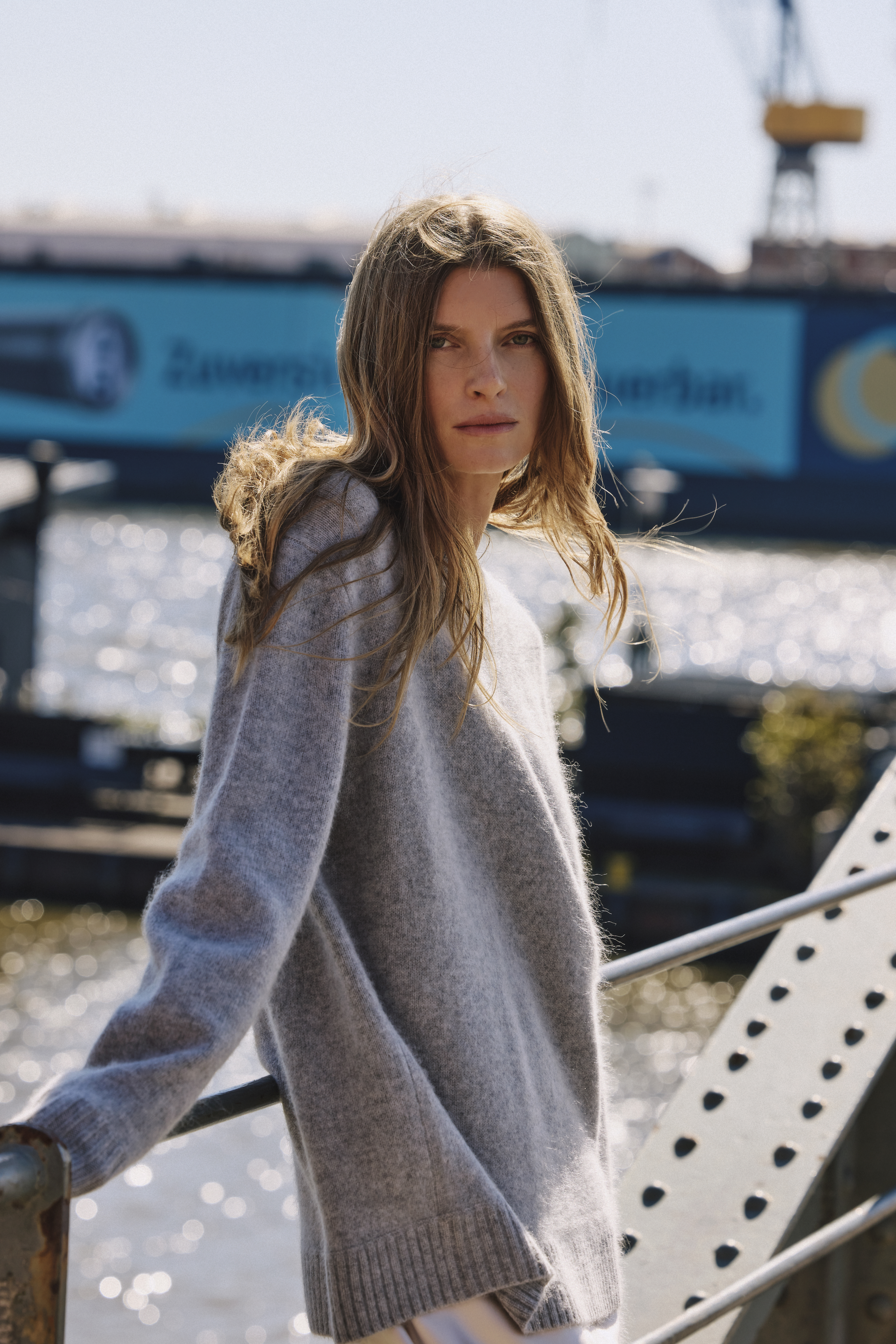 a woman wearing a grey pullover and a white skirt