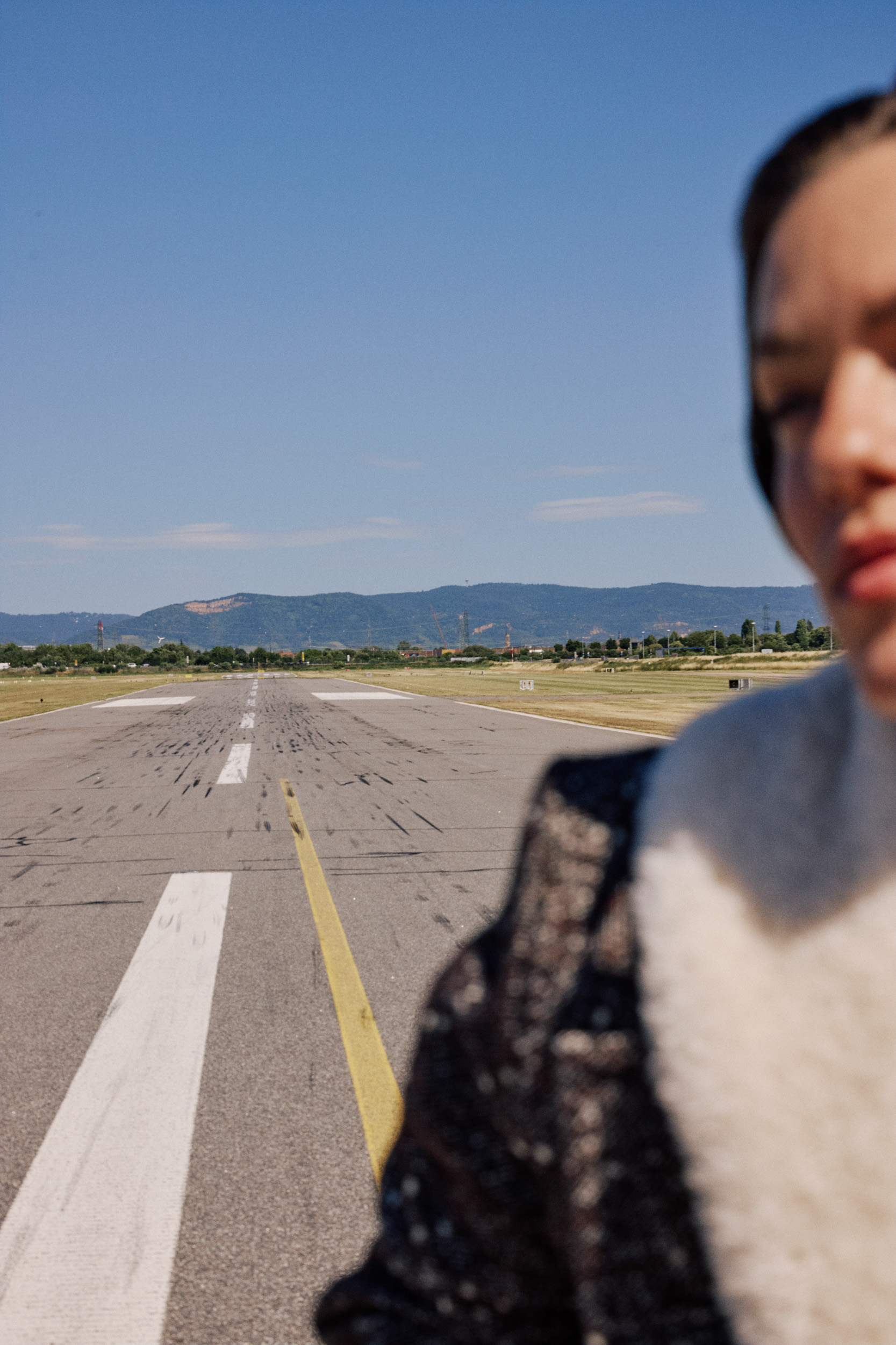 image of a female model running on airport runway wearing winter coat