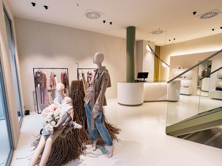 Eingangsbereich des Dorothee Schumacher Geschäfts in Dresden mit eleganten Schaufensterpuppen, Kleiderständern und einer modernen weißen Theke.