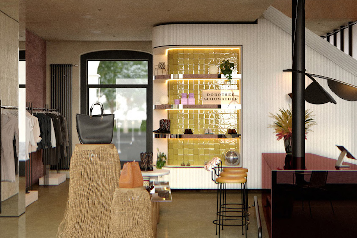 Eingangsbereich des Dorothee Schumacher Stores in München mit einer beleuchteten Auslage mit gelben Fliesen, einer schwarzen Handtasche auf einem Sockel und Kleiderständern.