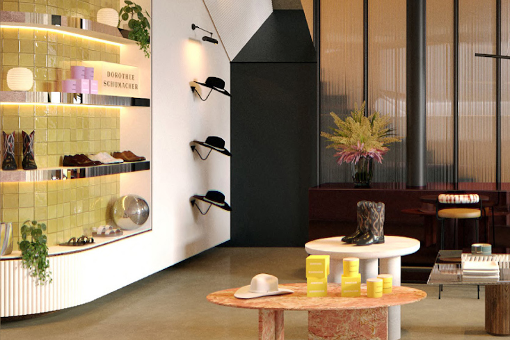 Detailansicht einer Auslage im Dorothee Schumacher Store in München mit gelb gefliesten Regalen, Hüten an der Wand und verschiedenen Accessoires und Schuhen auf Tischen.