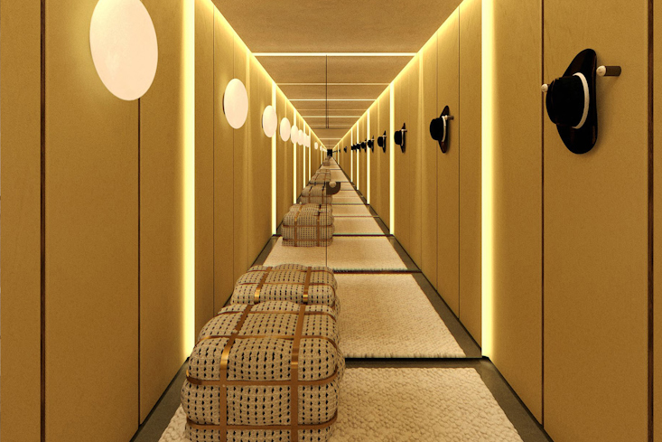 Ein langer, goldfarbener Flur im Dorothee Schumacher Store in München mit Sitzbänken und Hüten an den Wänden, der eine tiefe Perspektive erzeugt.