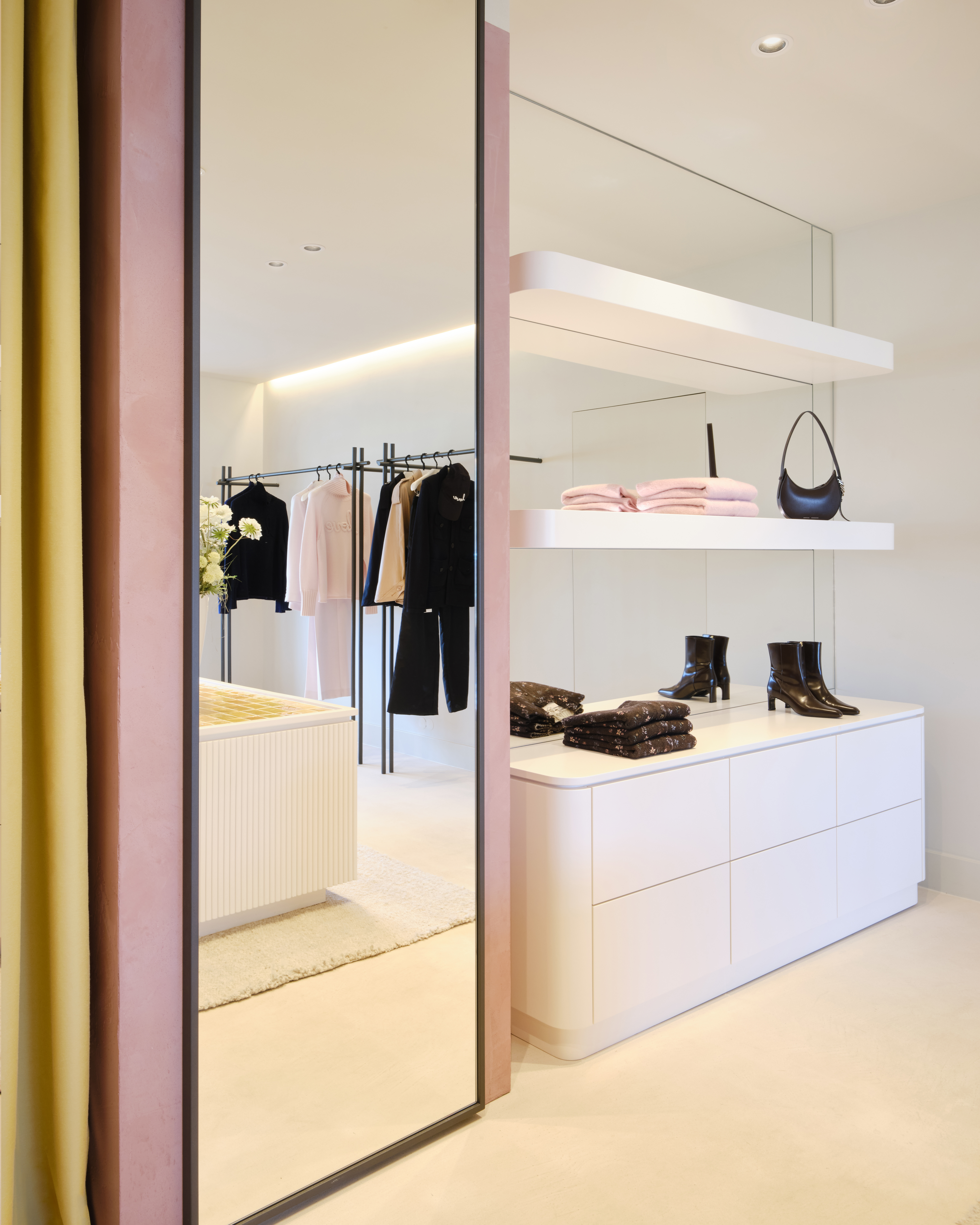 Innenansicht des Dorothee Schumacher Geschäfts mit großen Spiegeln, Kleiderständern und Regalen mit Schuhen und Accessoires.
