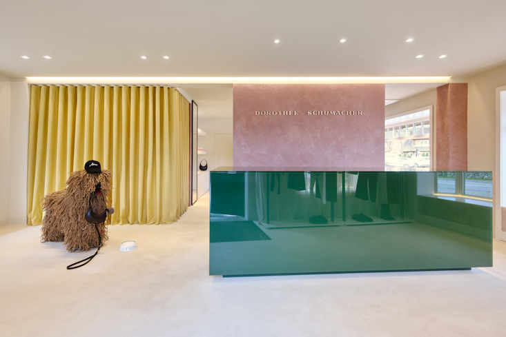 Dorothee Schumacher Boutique auf Sylt – moderner Eingangsbereich mit grünem Glas-Counter, rosa Wand und minimalistischem Store-Design.
